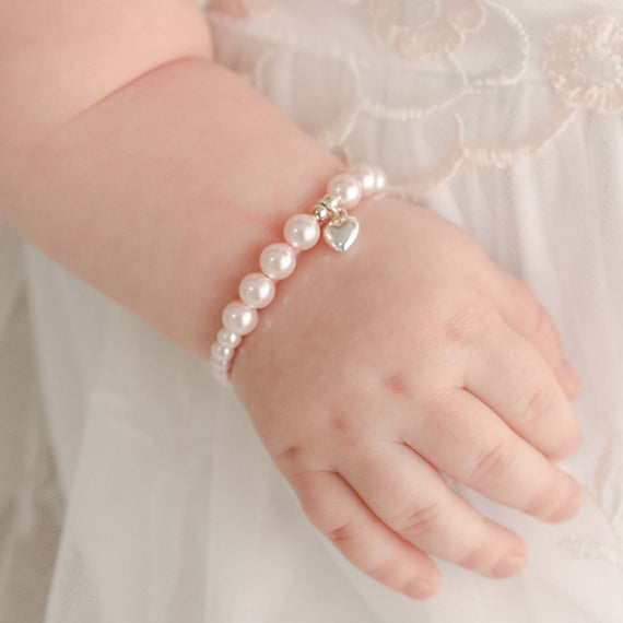 Baby girl wearing the Pink Luster Pearl Bracelet with Silver Heart Charm. Silver heart charm is made from sterling silver.