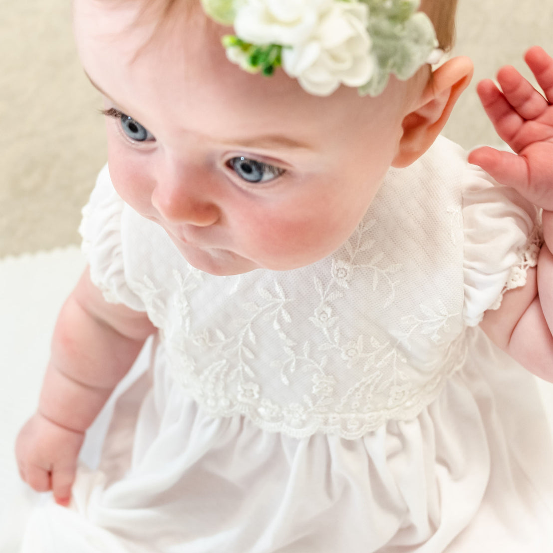 Closeup of baby girl wearing Ella layette, featuring a lace bodice 