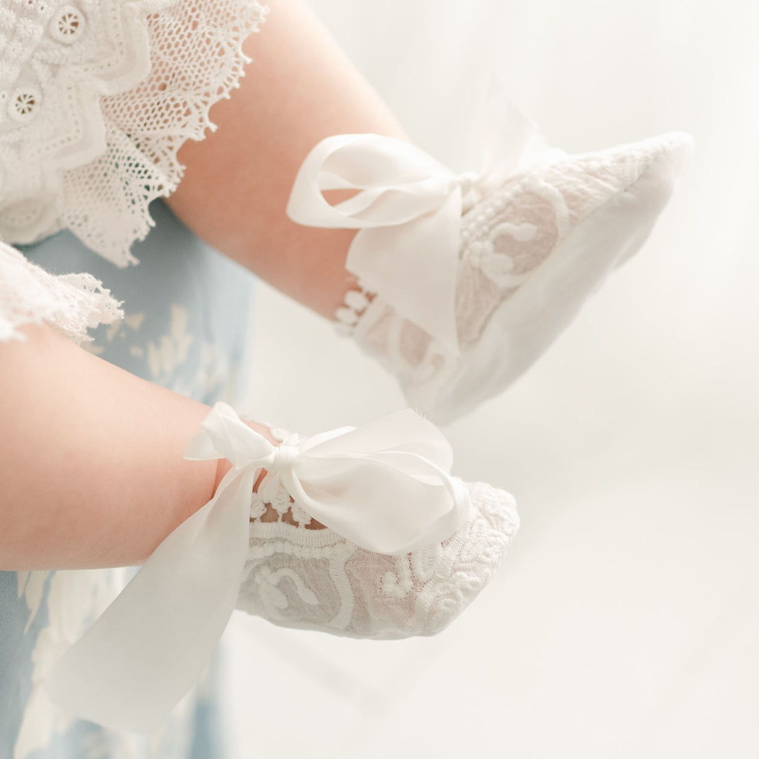 Detail of the Emily Booties made from a soft cotton lace in light ivory and adorned with a unique venice lace trim. Silk ribbon ties help keep the booties snug.