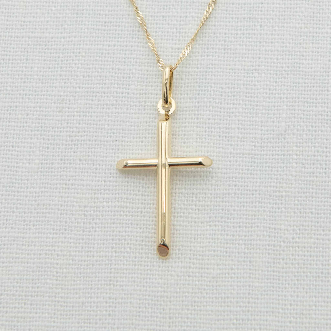 Cylindrical solid gold cross charm with angled ends on chain
