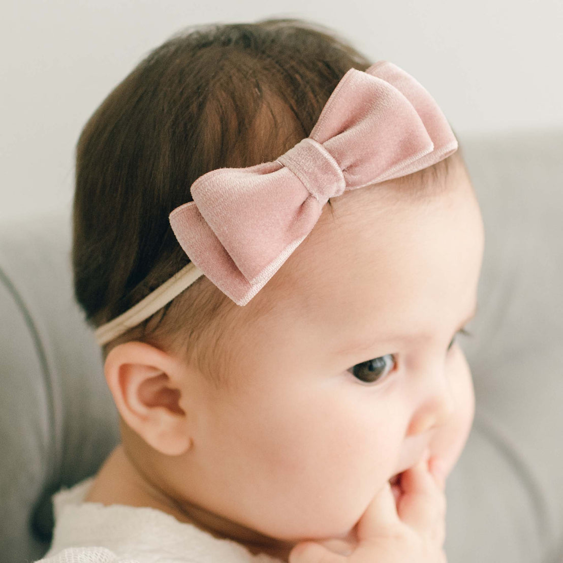 Baby girl wearing the mauve Emily Velvet Bow Headband with hand-stretched nylon band.