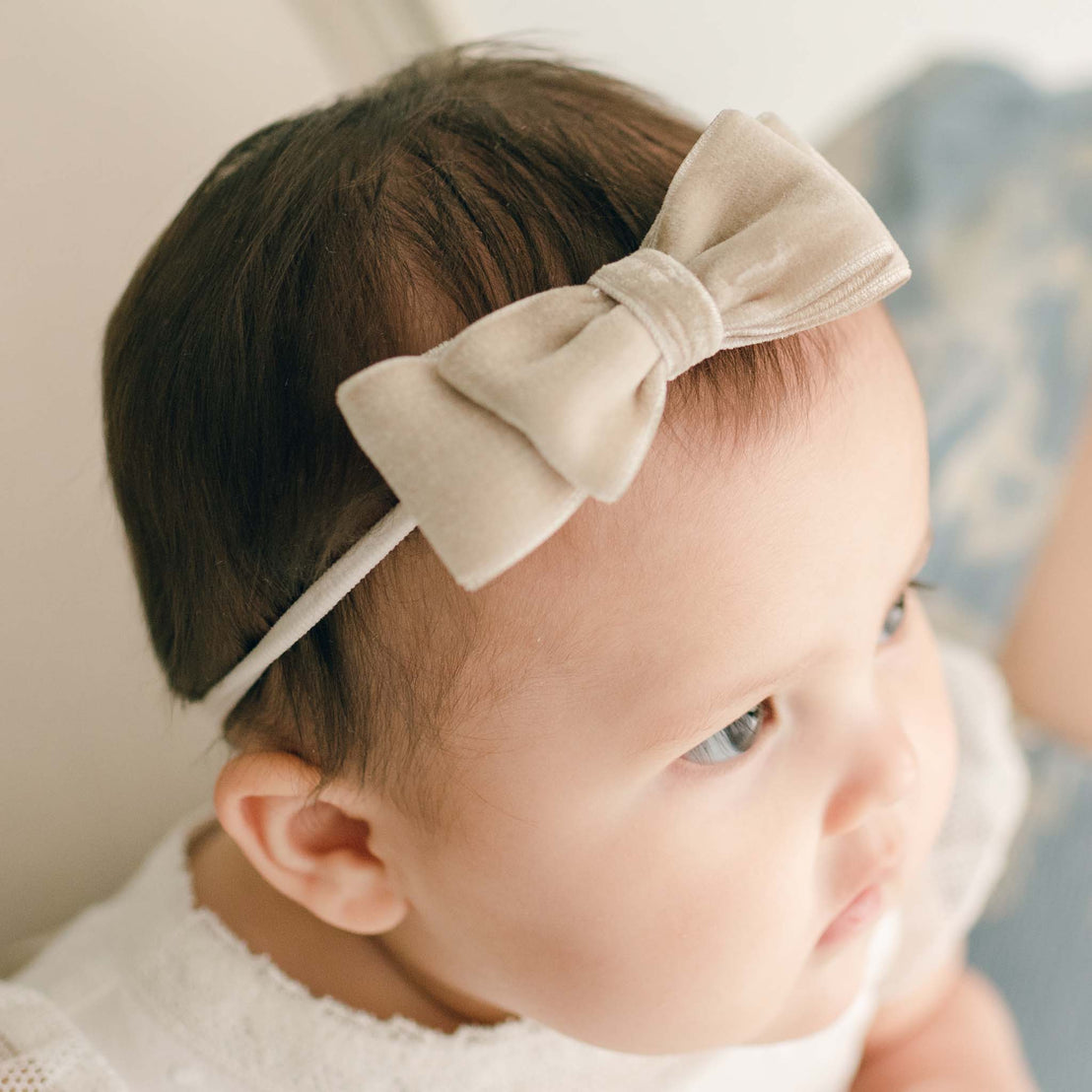Baby girl wearing the tan Emily Velvet Bow Headband with hand-stretched nylon band.