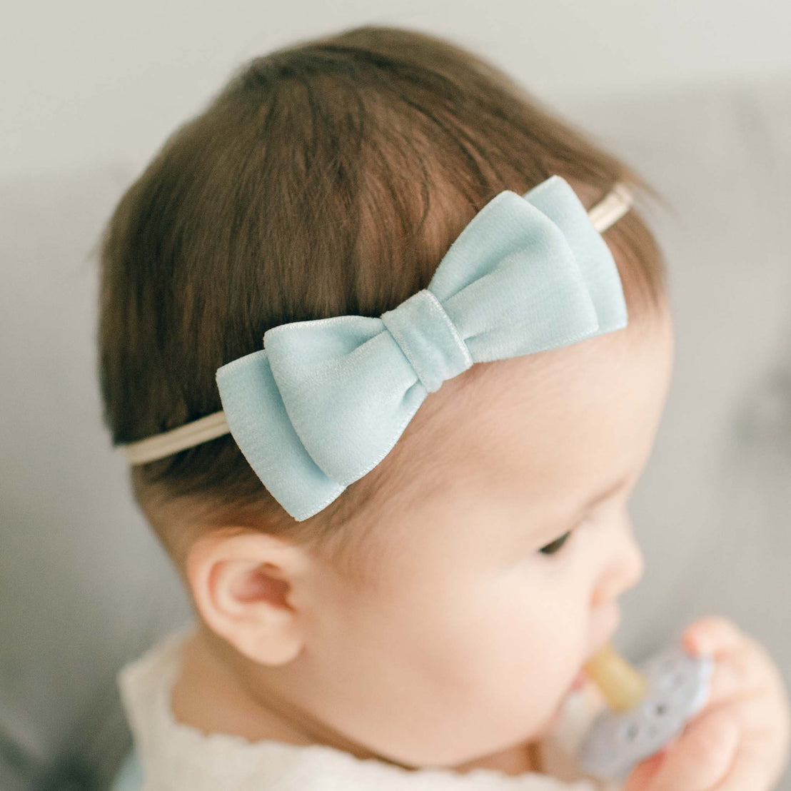 Baby girl wearing the powder blue Emily Velvet Bow Headband with hand-stretched nylon band.