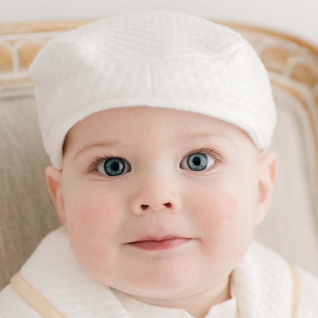 Close up photo showcasing the Liam Baby Newsboy Cap made from white quilt