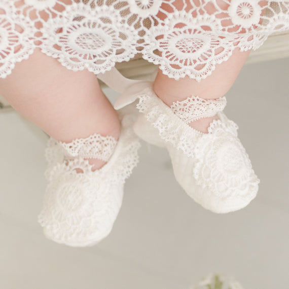 Baby girl feet wearing poppy lace christening booties. 