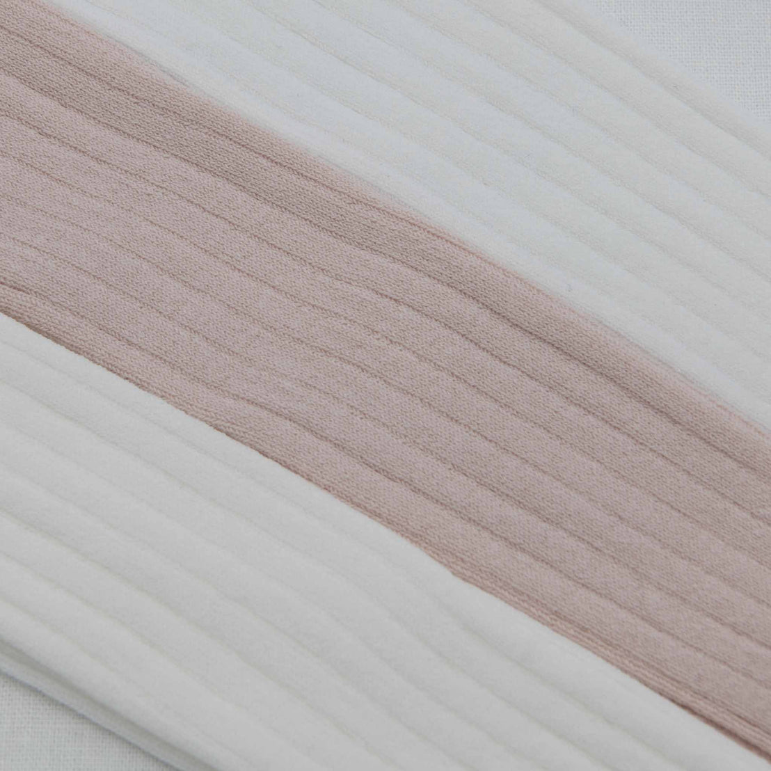 Close-up of a pair of Ribbed Tights with alternating white and pale pink vertical stripes. The texture appears soft with pronounced ridges in the weave.