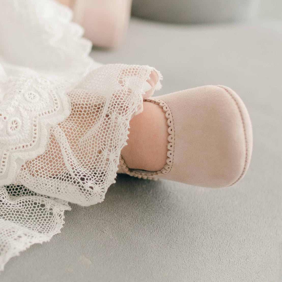 Baby girl wearing the blush Emily Suede Tie Mary Janes. Shoes are made with a soft suede with tie detail closure.