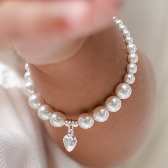 Close up photo of the Silver Heart bracelet on a baby girl. Part of our christening jewelry collection.