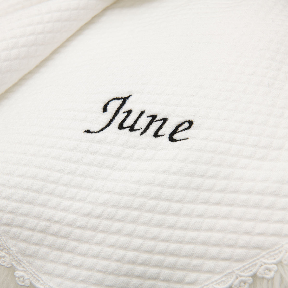 Close-up of a stylish white textured fabric with the name "June Personalized Blanket" embroidered in black cursive script.