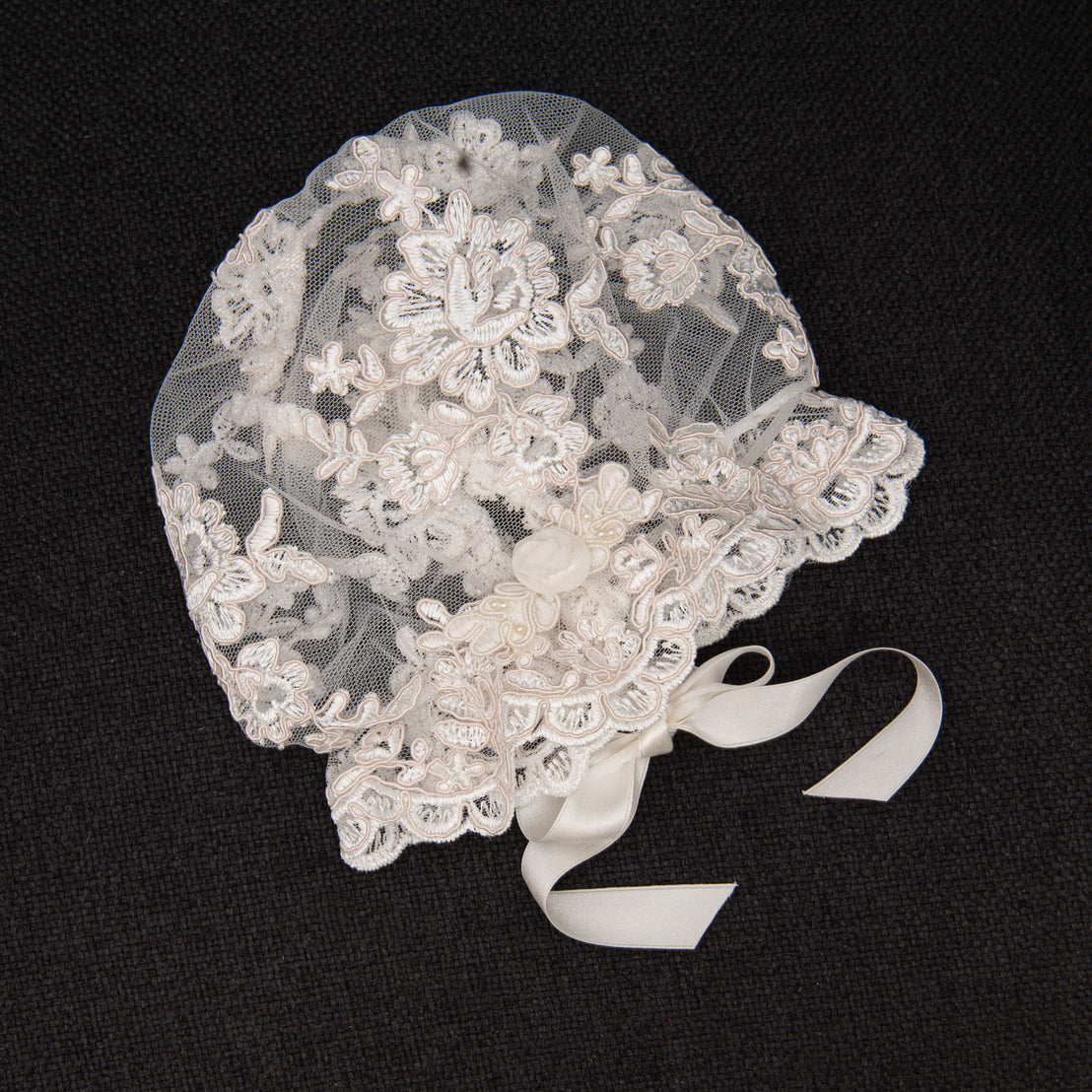 Flat lay photo of lace bonnet, part of the Penelope christening collection.