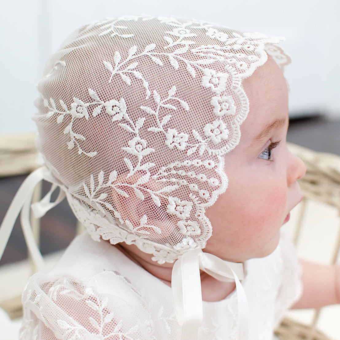 Profile of baby girl wearing a lace bonnet in the Ella baptism collection