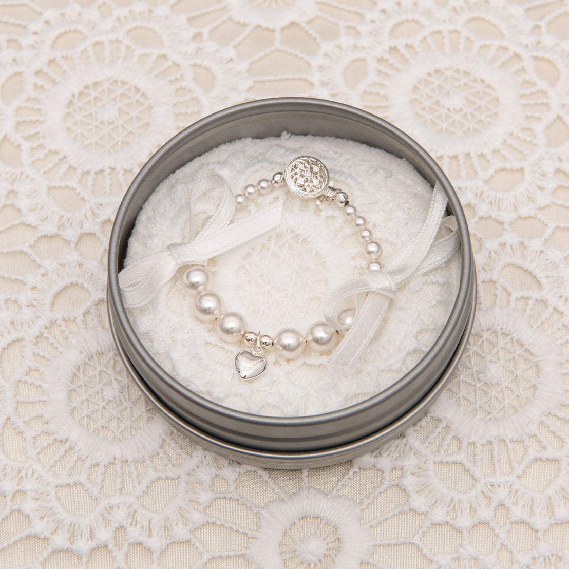 Baby jewelry: White luster pearl bracelet photographed in packaging. 