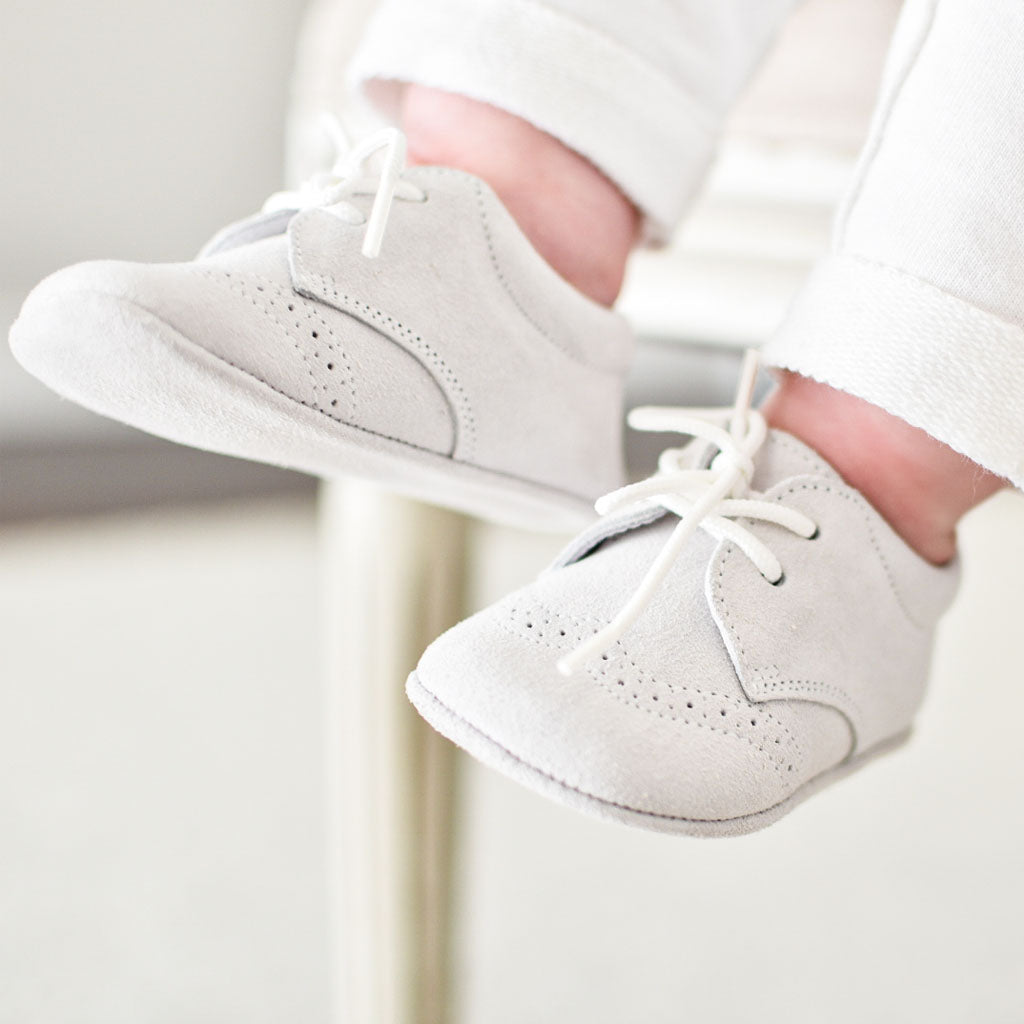 Photo of a baby wearing a pair of the Dove Grey Suede Shoes crafted with a super soft, dove grey suede with detailed edging