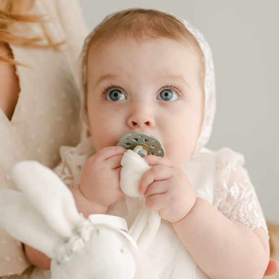 baby girl using a bibs pacifier in sage