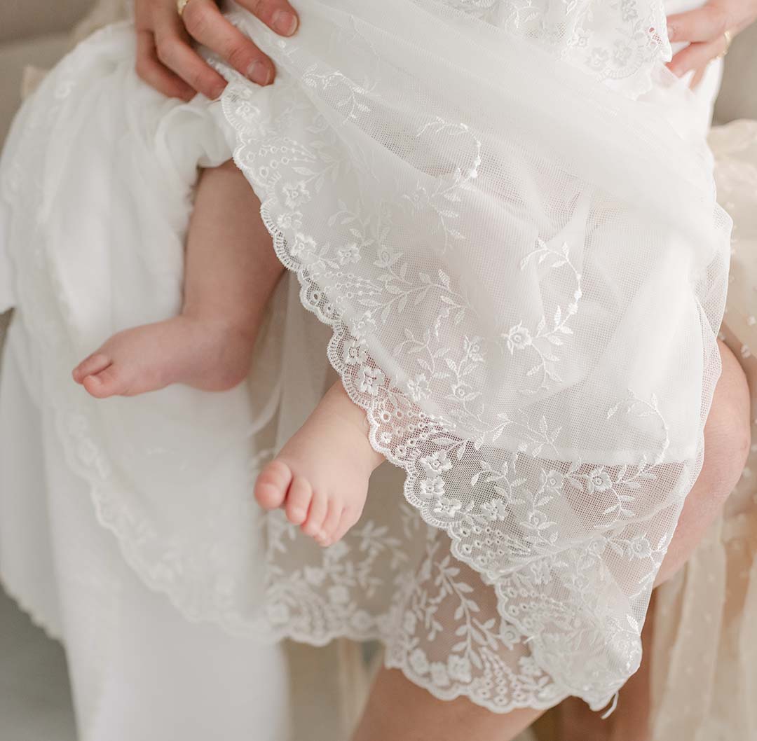 baby feet popping out of the bottom of the lace christening gown