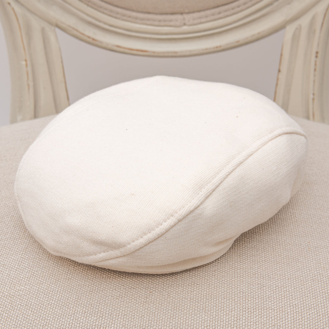 Flat lay photo of the ivory french terry Braden Newsboy Cap on a chair