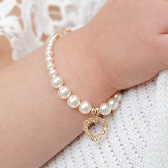 Baby girl pearl bracelet with gold heart charm on baby