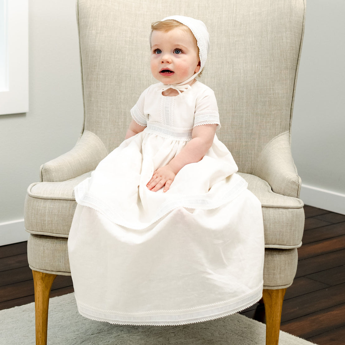 Baby boy making a funny face wearing the Rowan linen boys baptism gown.