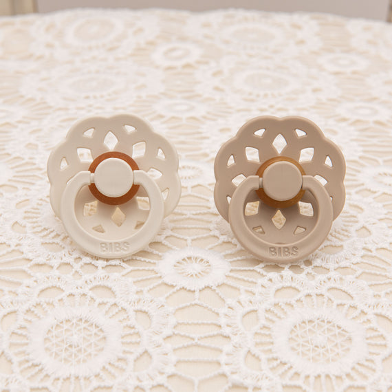 Two baby pacifiers next to each other in 2 colors: Ivory and Vanilla. 