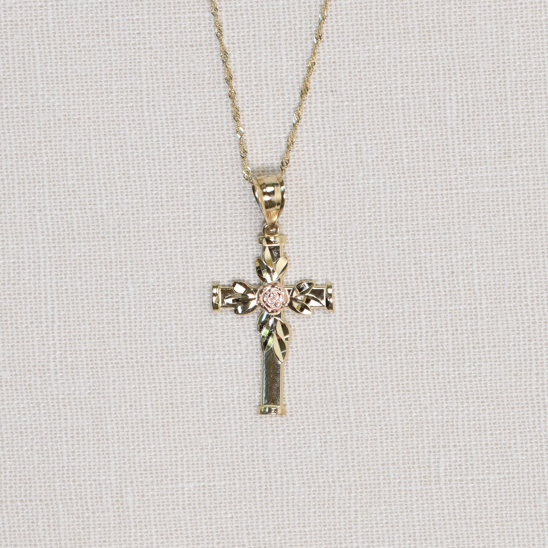 Solid gold cross with gold leaves and rose gold rose detail on chain