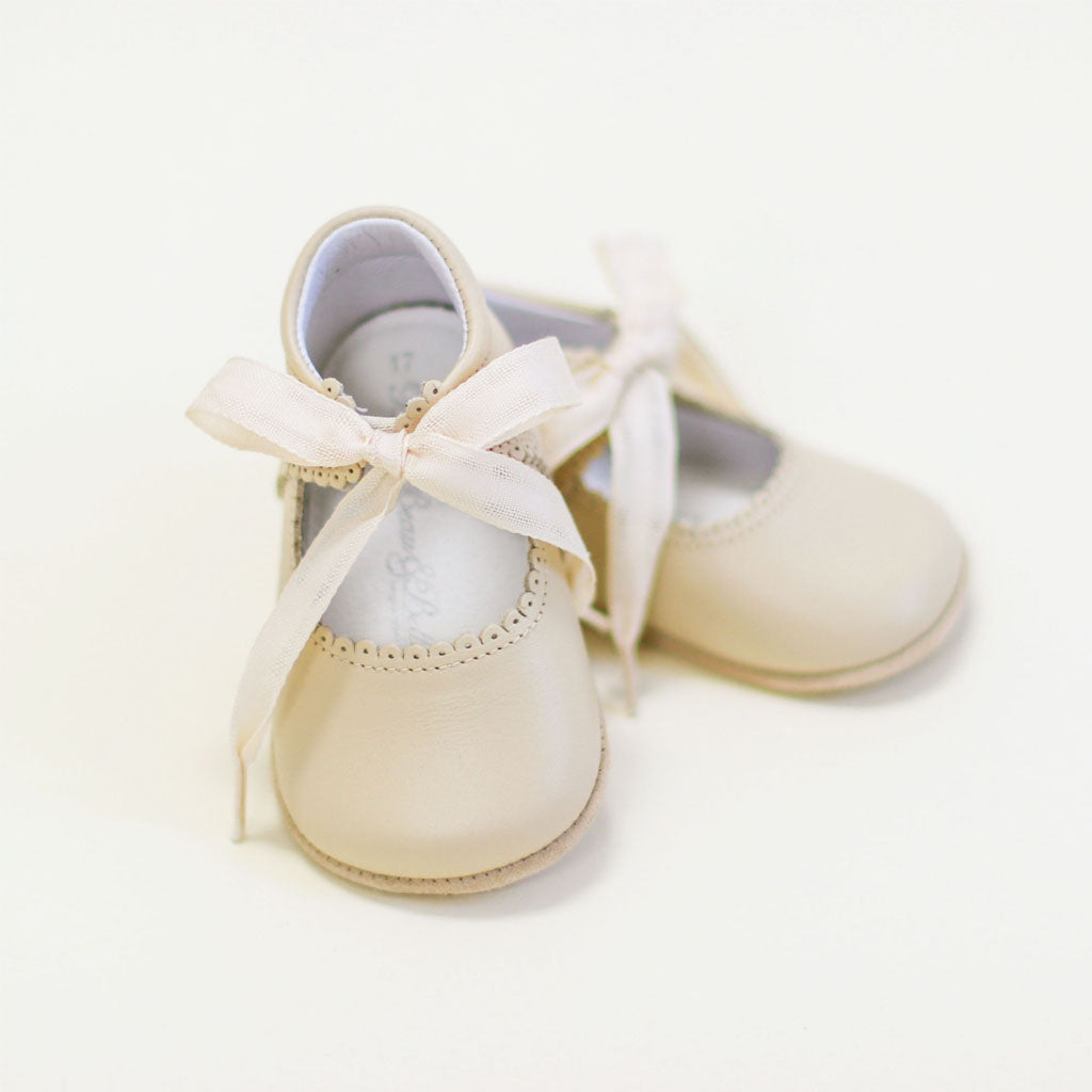 A flat lay photo of the Tan Tie Mary Janes crafted with tan matte leather with beautiful scallop edge detail and complimenting cotton ribbon tie