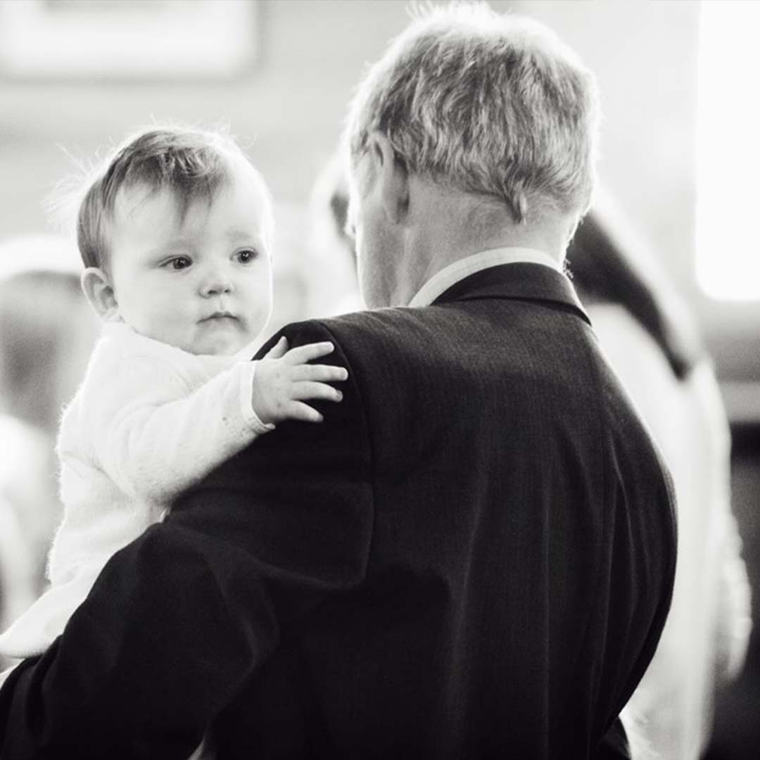 A black and white photo of a baby boy with his grandfather