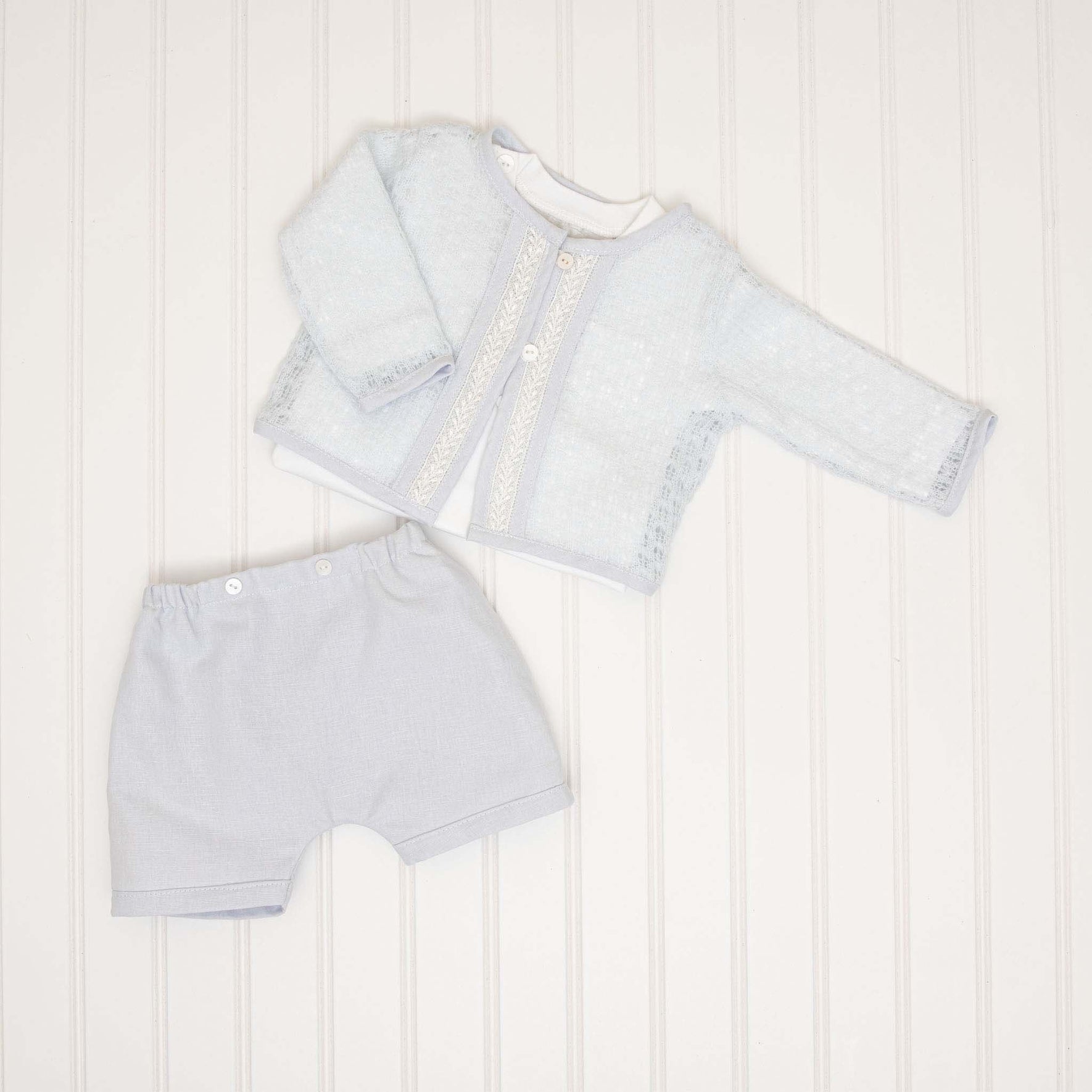 A detailed flat lay of the threeHarrison Sweater 3-Piece Shorts Suit, including a light blue lace-trimmed sweater, matching shorts, and an undershirt.