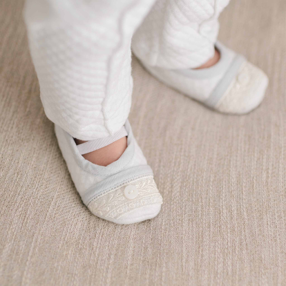 Close up of baby wearing the Harrison Booties that are made with soft white textured cotton and soft elastic straps