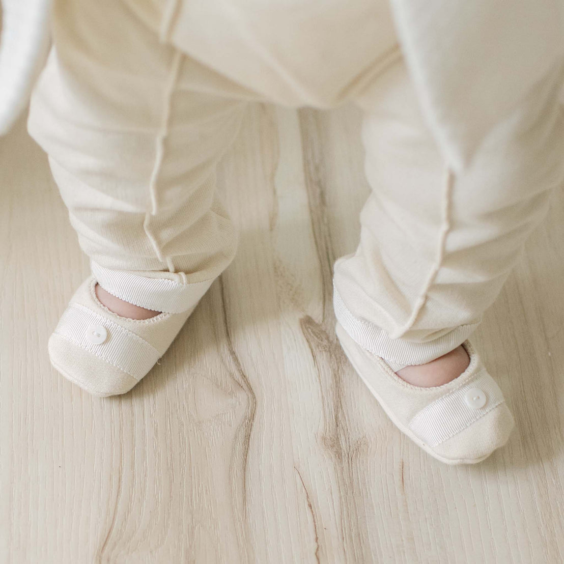 Baby's feet wearing white socks on a wooden floor