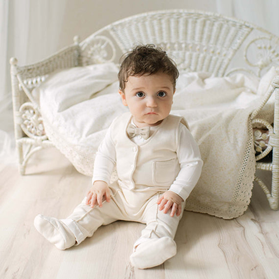 Baby in a natural ivory pants and vest suit sitting with a blanket