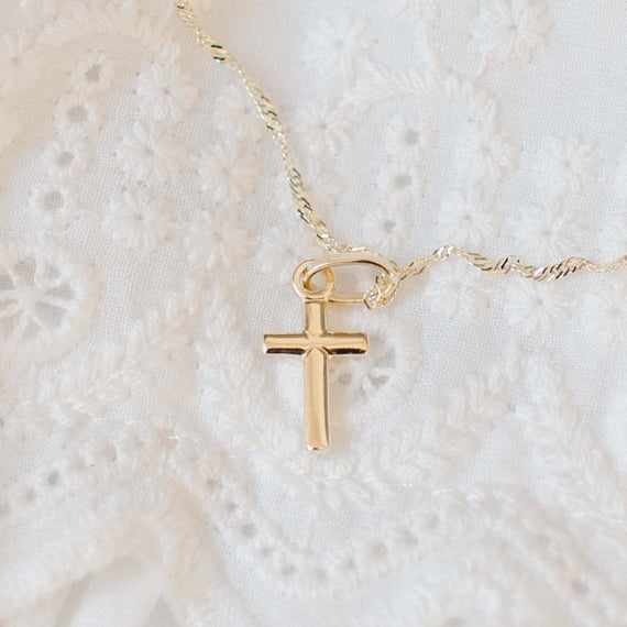 Small solid gold cross on chain with lace background