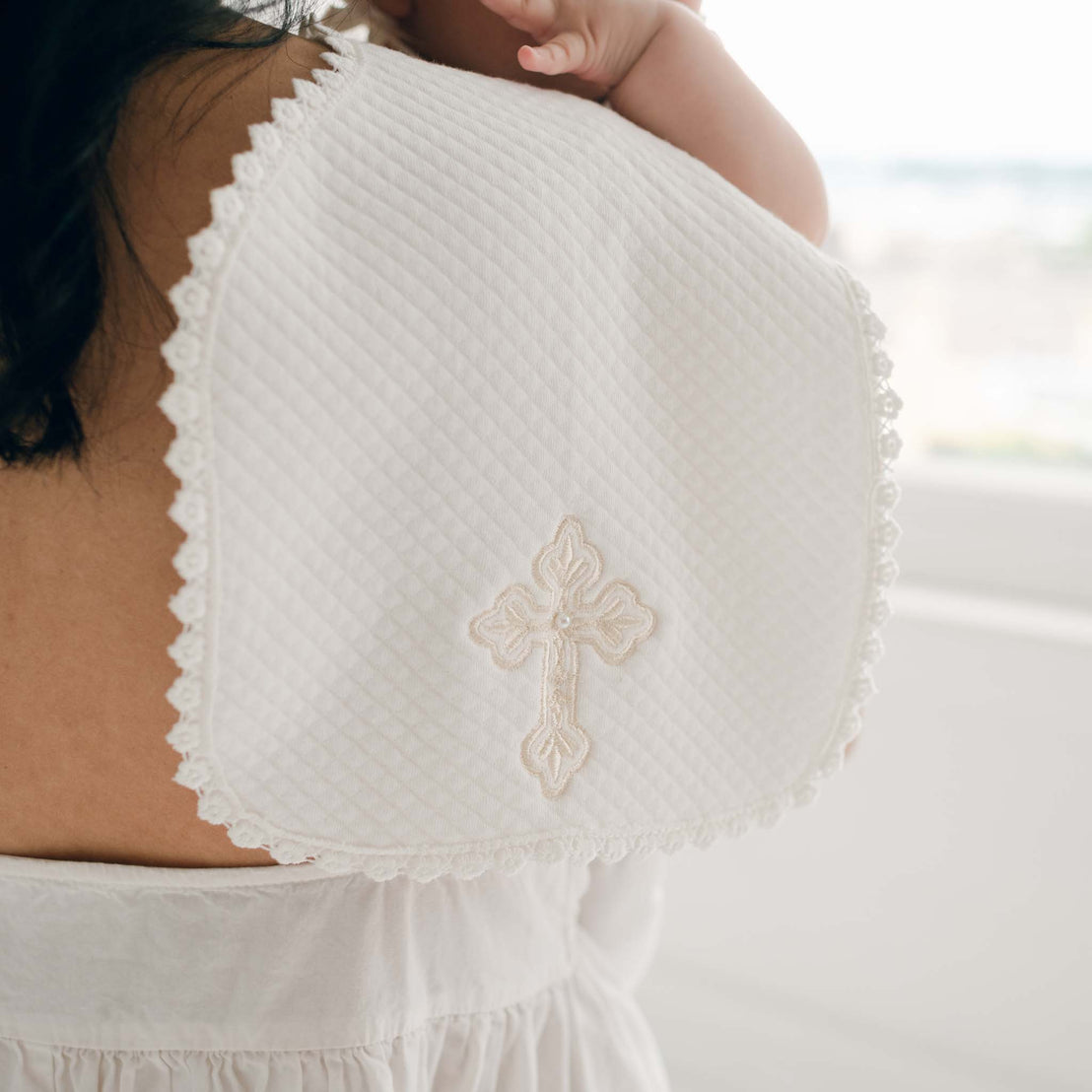 White embroidered cross blanket draped across a woman's shoulder