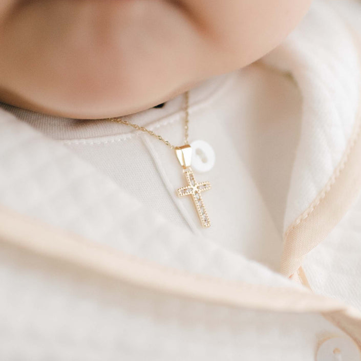 Gold and crystal cross charm necklace on baby