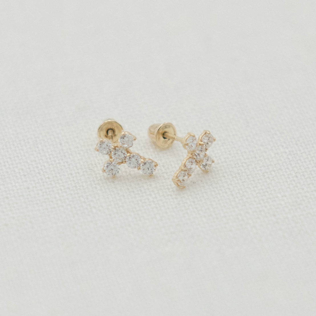 14k Gold & Stone Cross Earrings shown with delicate cross shapes and light-catching stone accents.