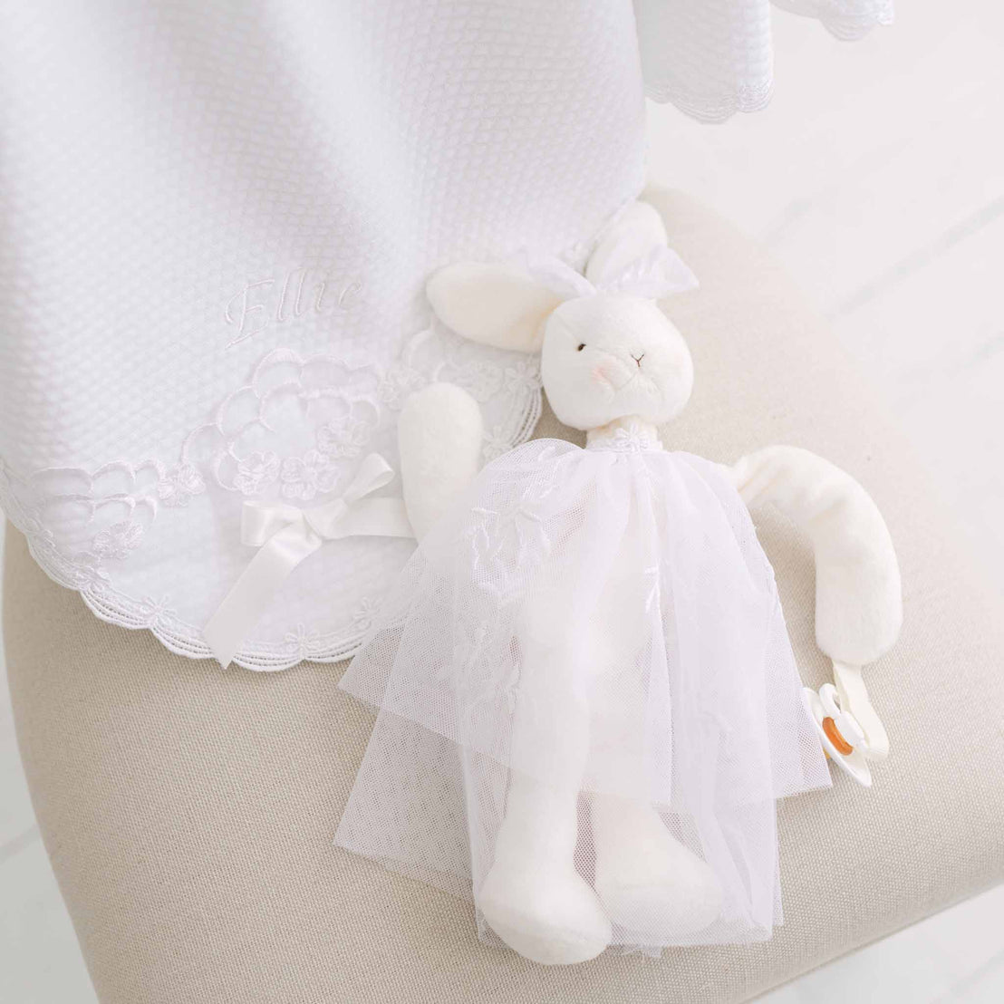 White plush bunny toy with lace skirt laid against a neutral background.