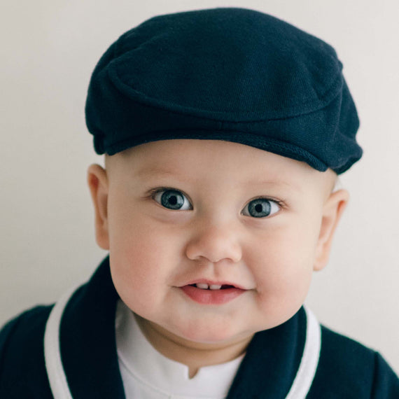 Smiling baby boy wearing the navy Elliott Newsboy Cap.