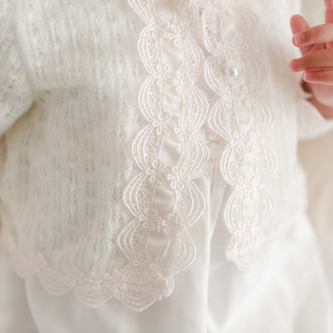 Close-up of a white knit sweater with lace trim