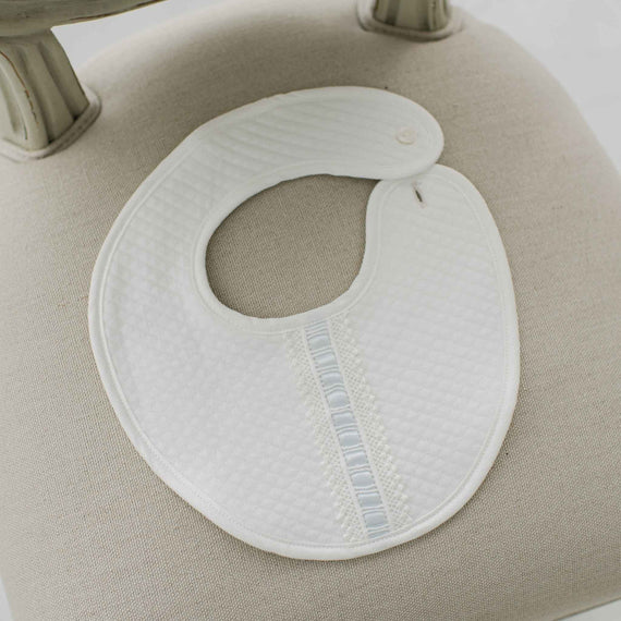 White bib with blue lace on a beige cushion