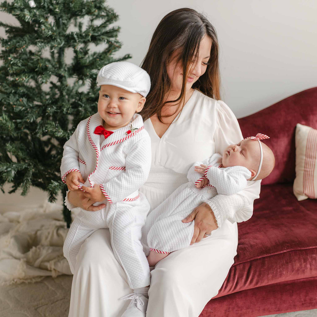 Woman holding two babies in front of a Christmas tree