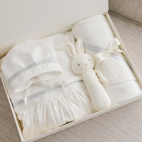The Owen Newborn Gift Set in a white box, including Layette Gown, Bonnet, bunny Rattle, and Blanket