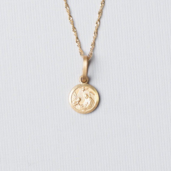Gold necklace with a round pendant on a light gray background