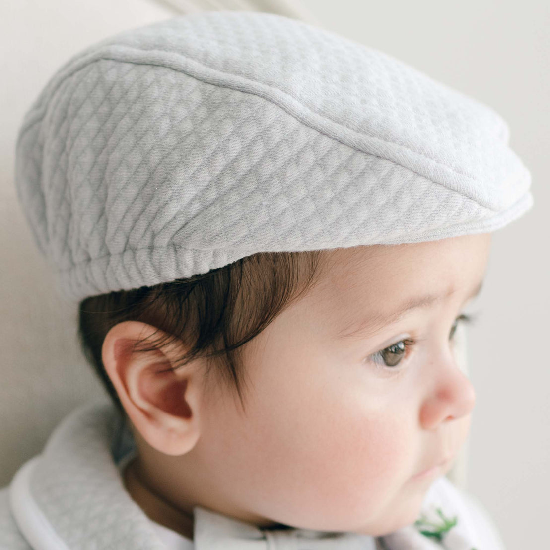 Baby wearing a gray cap with a neutral background