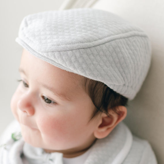 Baby wearing a textured gray hat against a neutral background