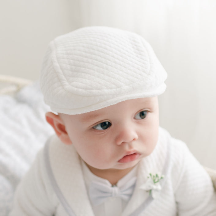 Close-up of an infant wearing the Harrison Newsboy Cap, crafted from white quilted fabric with a classic and refined style.