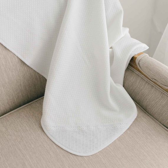 White quilt blanket draped over a beige chair.