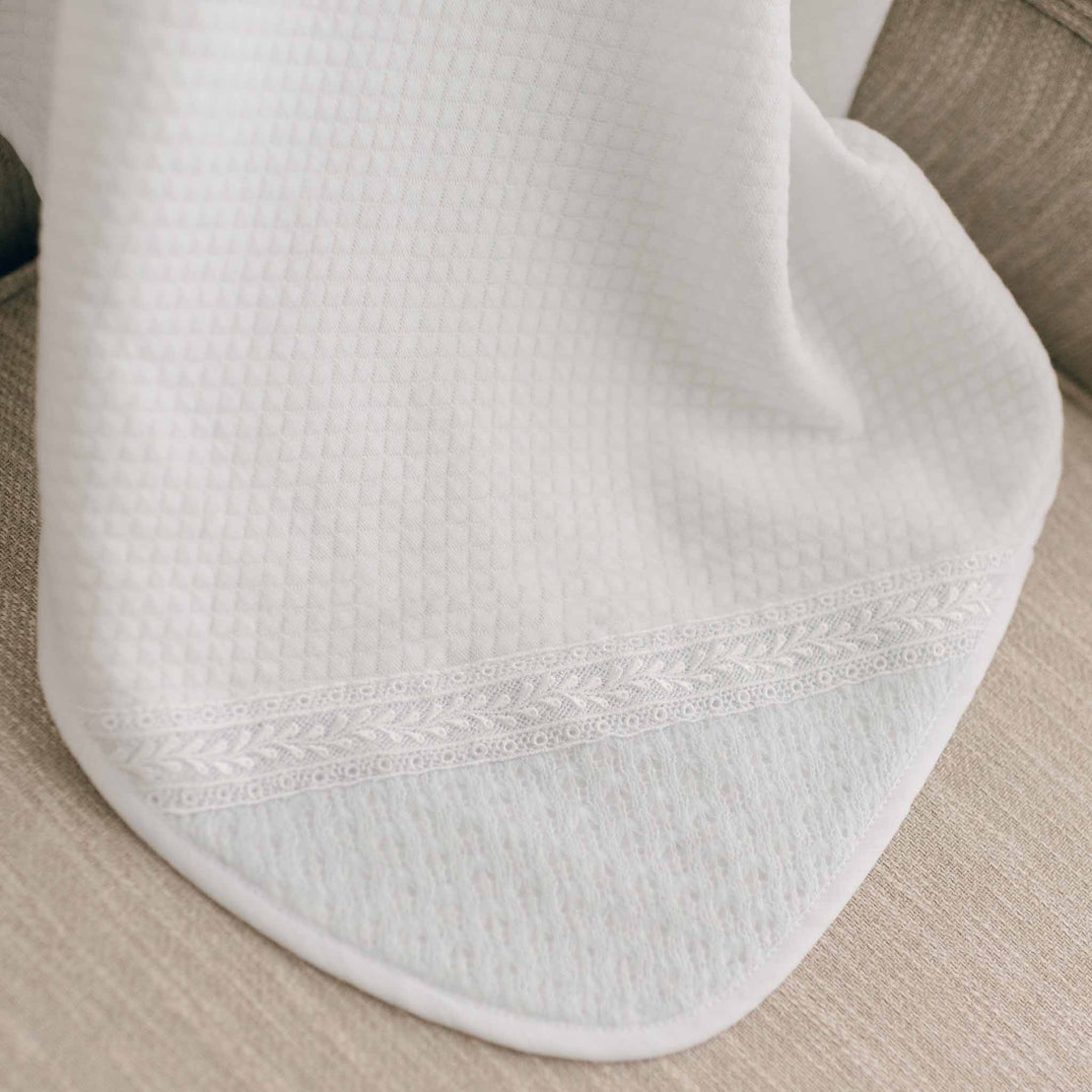 Close-up of a white quilt blanket draped over a beige chair.