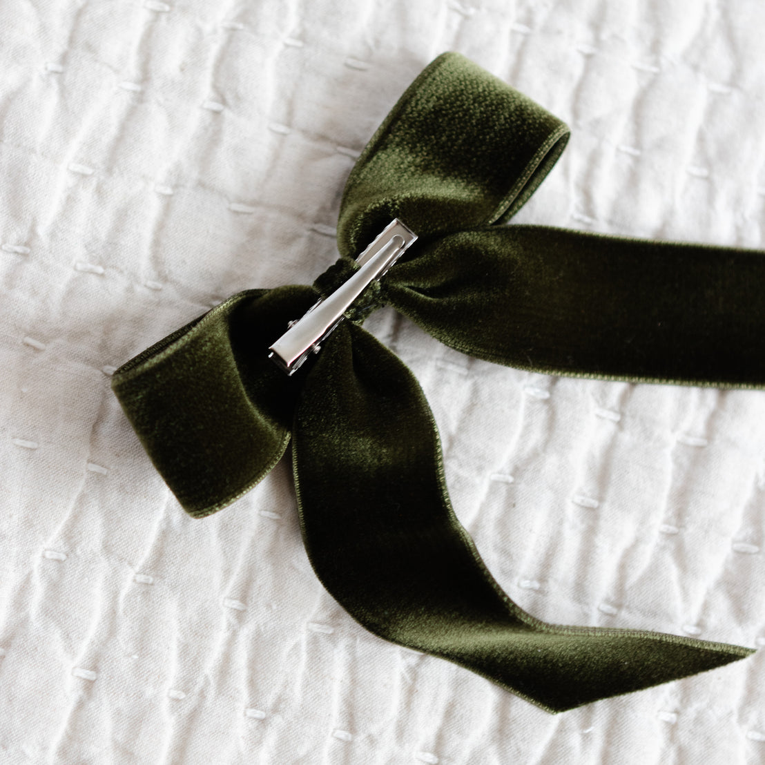 Green velvet ribbon with a silver clasp on a textured white background
