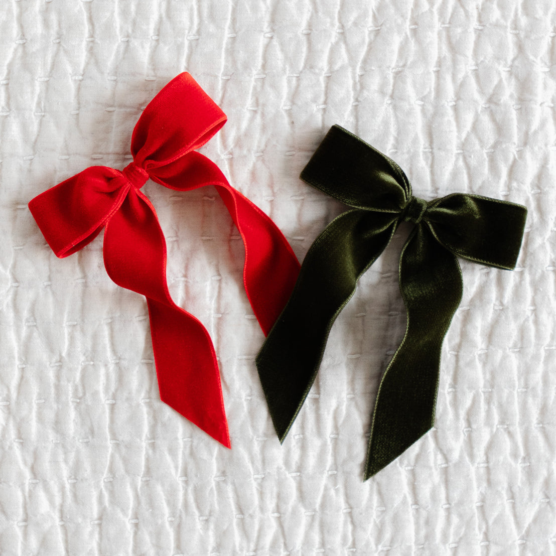 Red and green velvet bows on a textured white background