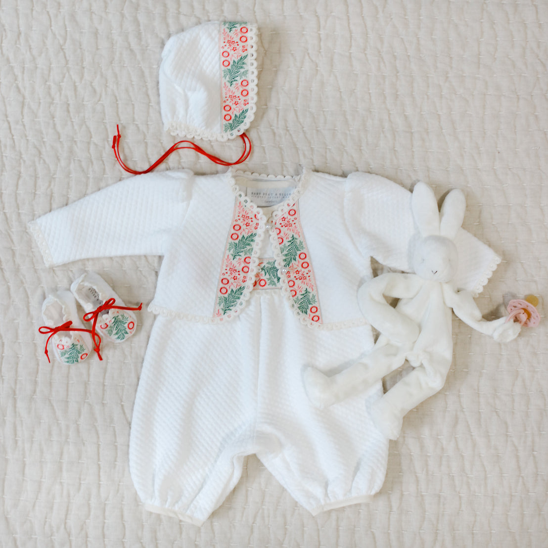 White baby outfit with floral details on a textured surface