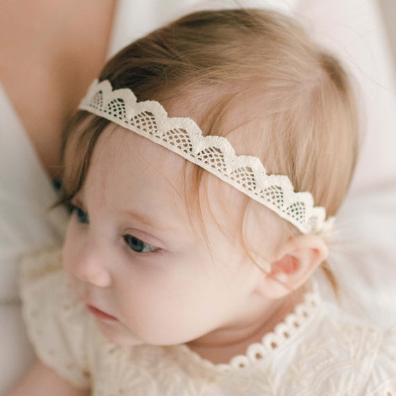 Baby wearing the Ingrid Lace Headband crafted with natural ivory cotton scallop lace